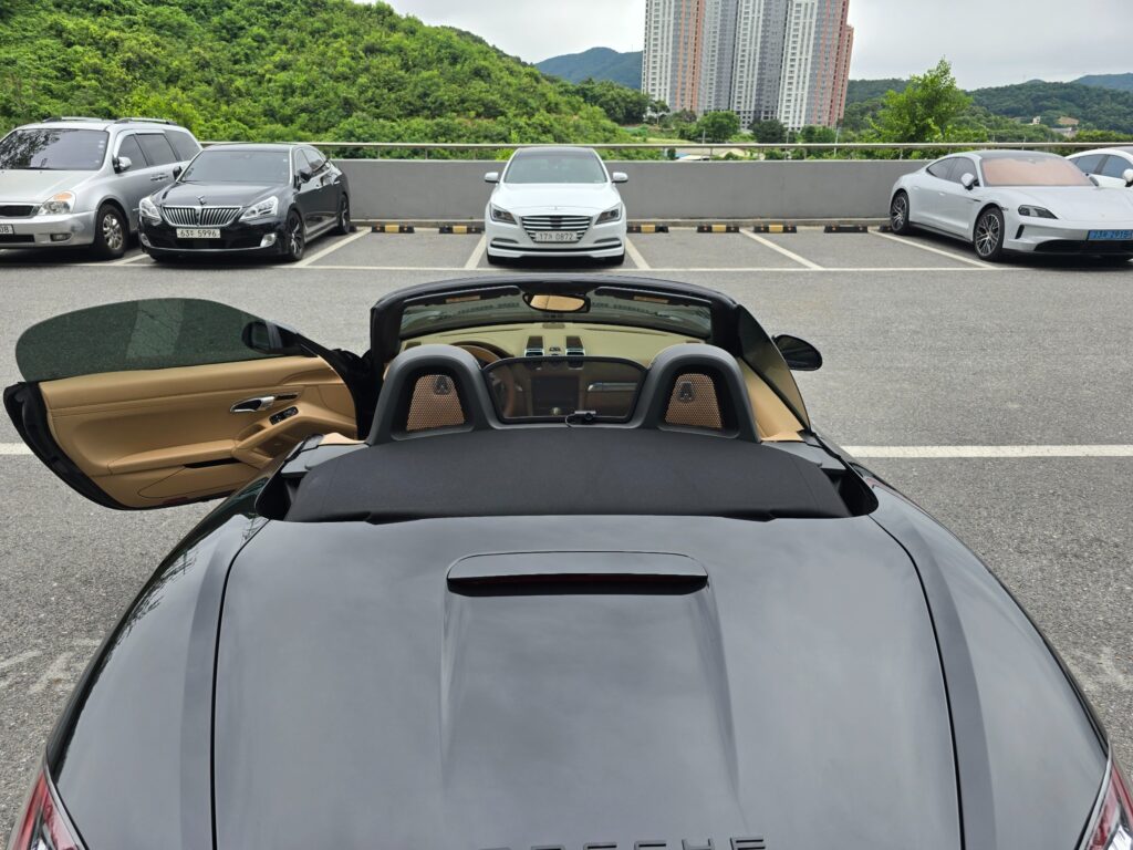 지붕을 연 검정 포르쉐 박스터의 후면 모습