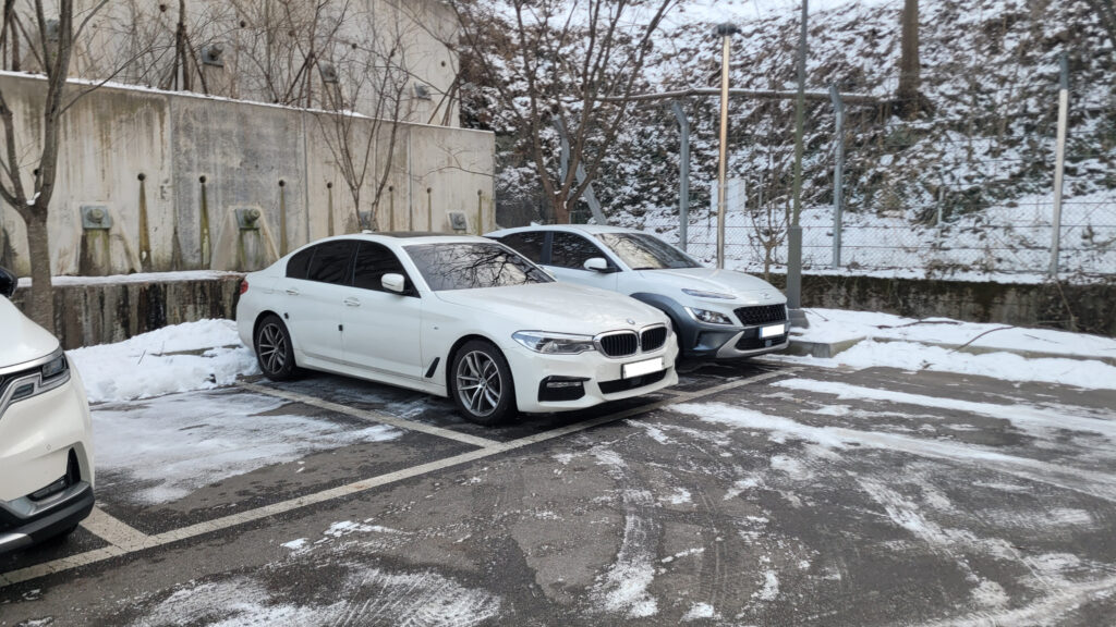 눈 내린 주차장에 세워진 흰색 BMW 520d